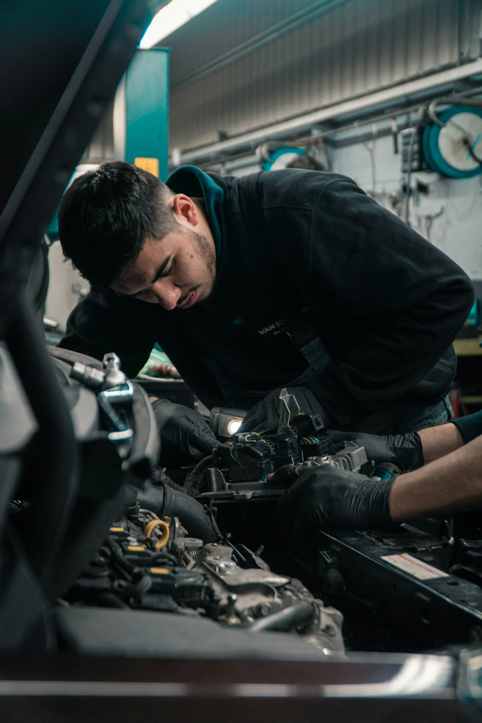 Technician leaning into an engine bay with a work light