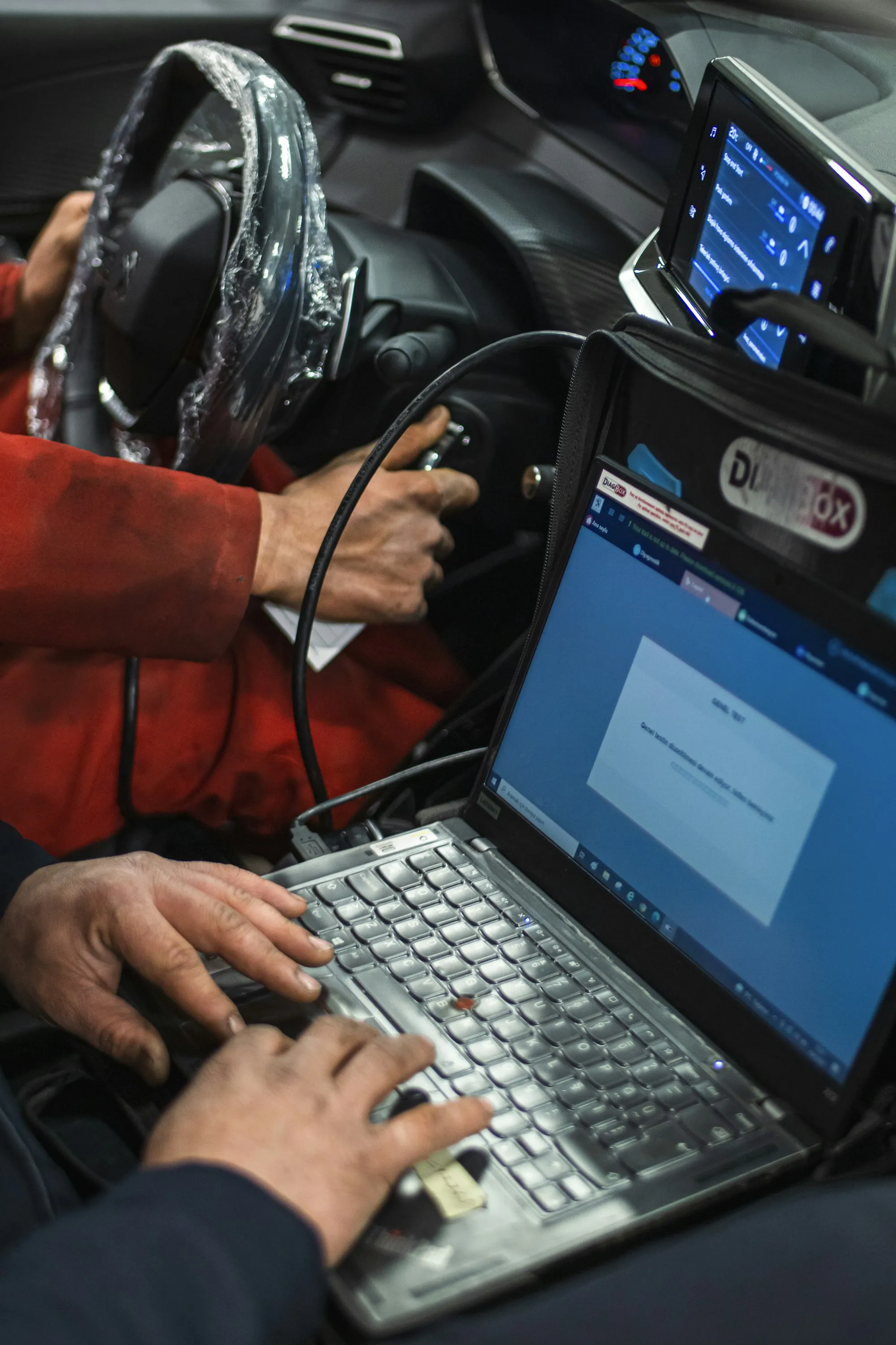 Technician connecting a diagnostic laptop to a vehicle