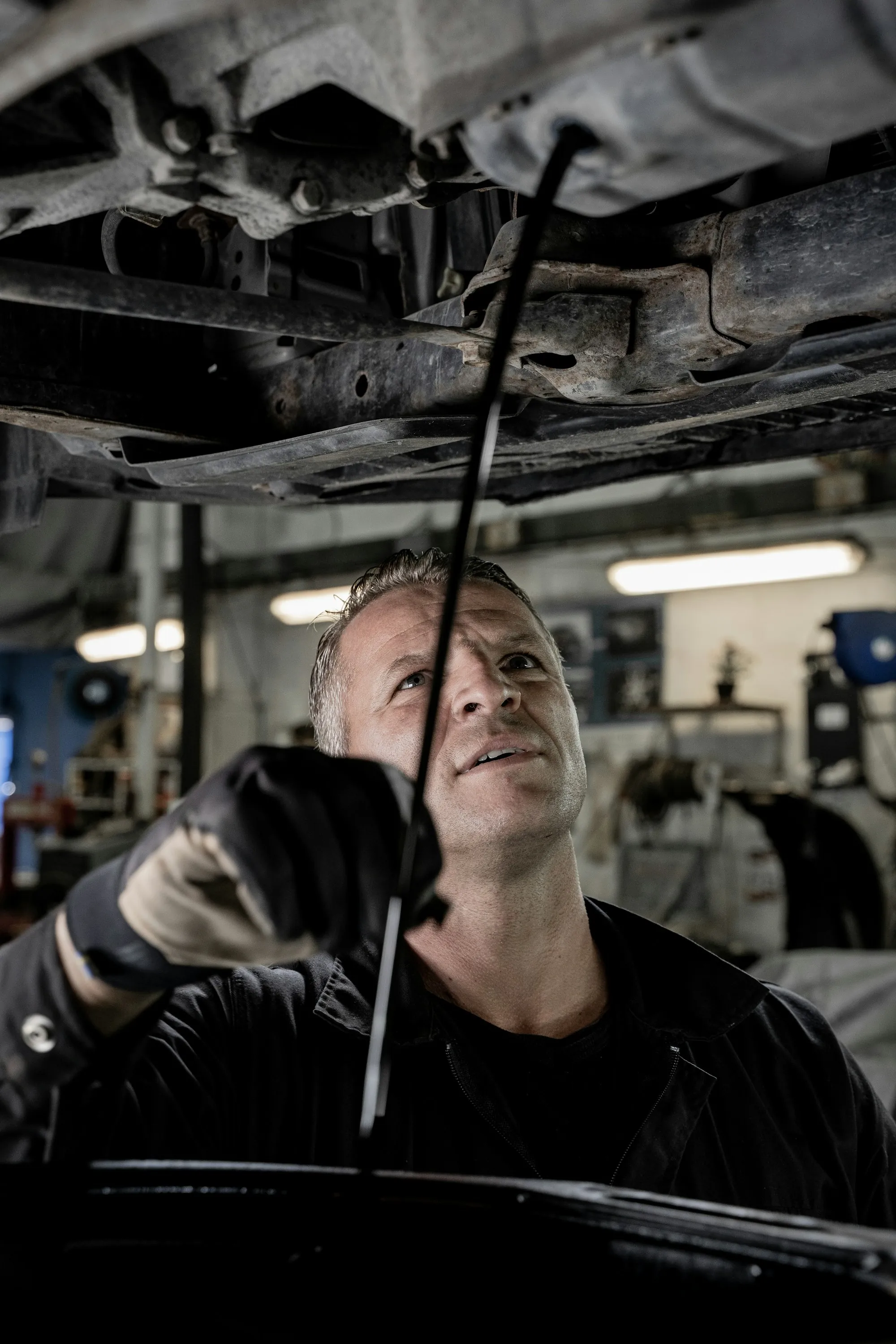 Mechanic working beneath a raised car in a repair bay