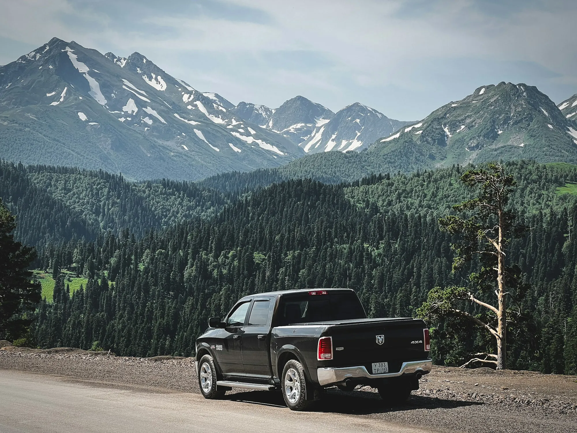 Black pickup truck parked below snow-capped mountains