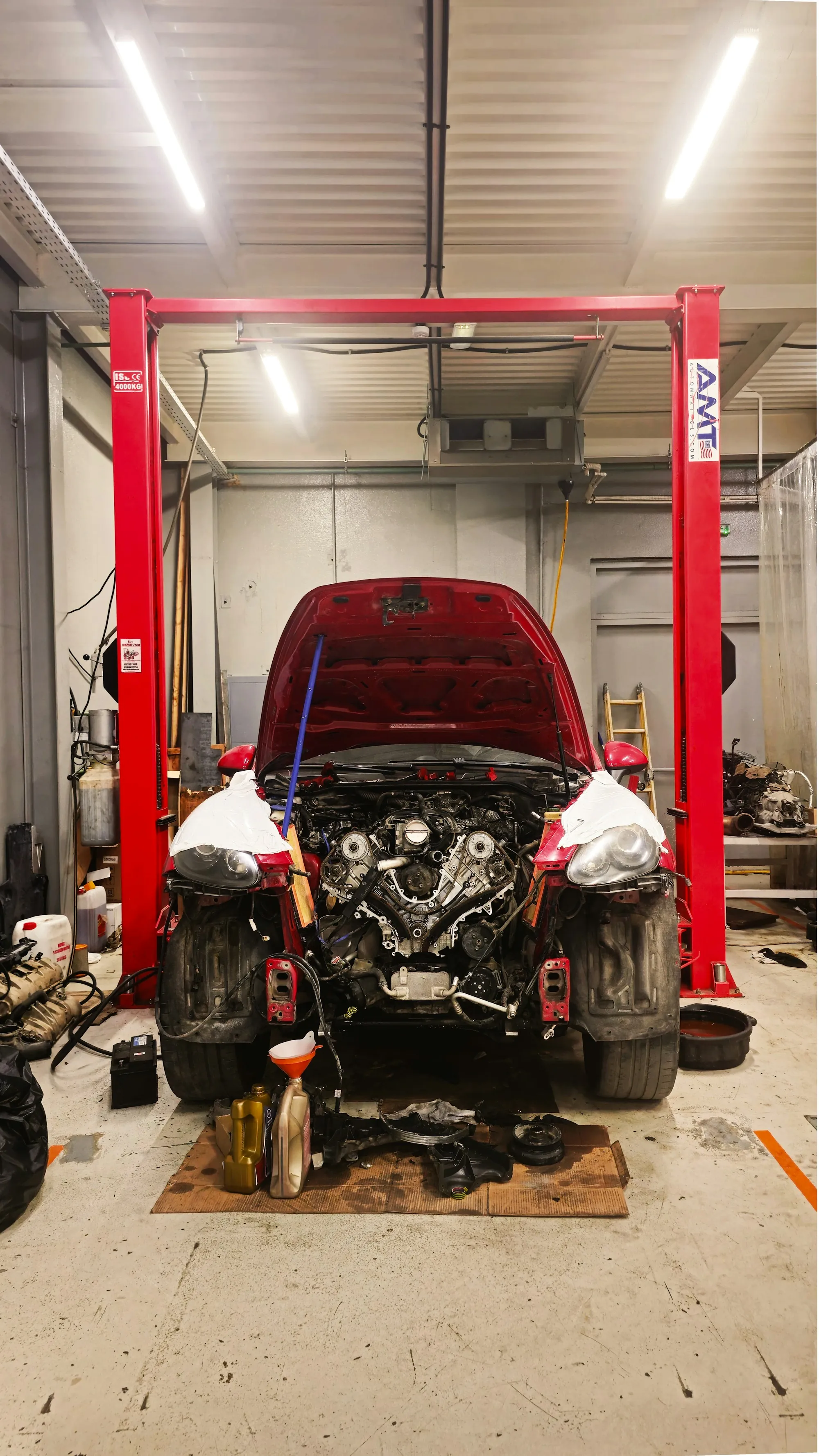 Red car on a two-post lift with its engine bay open